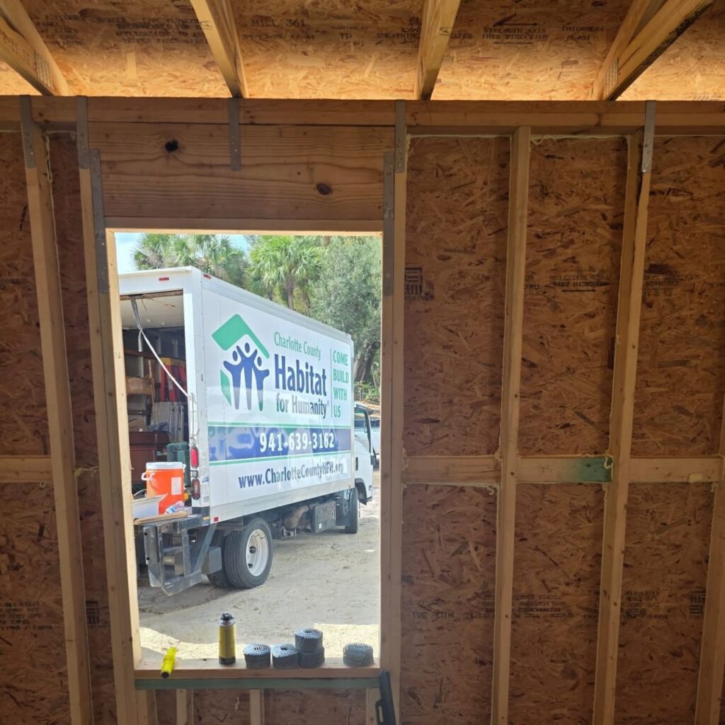 Habitat for Humanity truck seen through framed doorway of new home build in Charlotte County, Florida – supported by Lundstrom Home Inspections